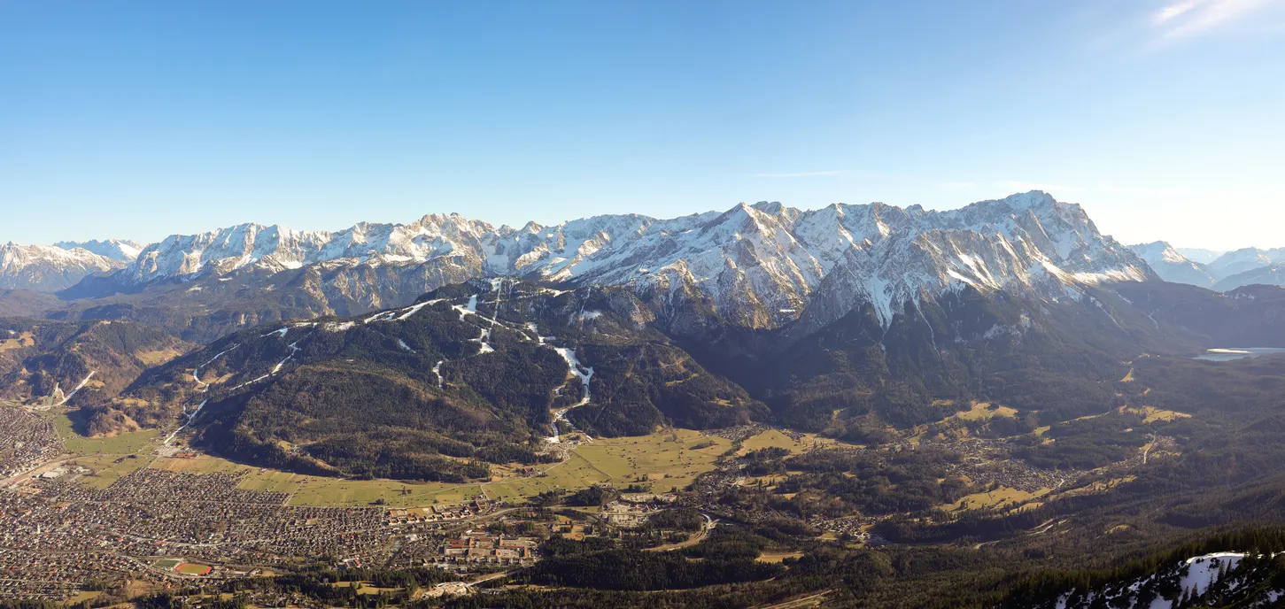Blick auf Garmisch-Partenkirchen vor der Zugspitze (in der Gebirkskette ganz rechts). Foto: Wilfried Ballnath - Adobestock